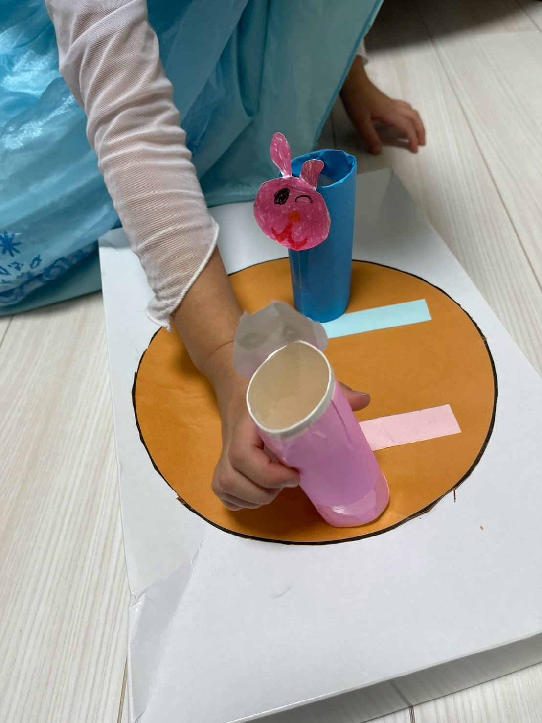 紙コップと色紙の工作で遊ぶお子さまの手元